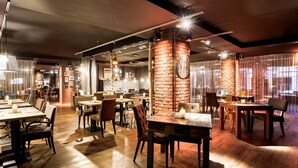 Un restaurante con mesas y sillas de madera, paredes de ladrillo y luces colgantes.