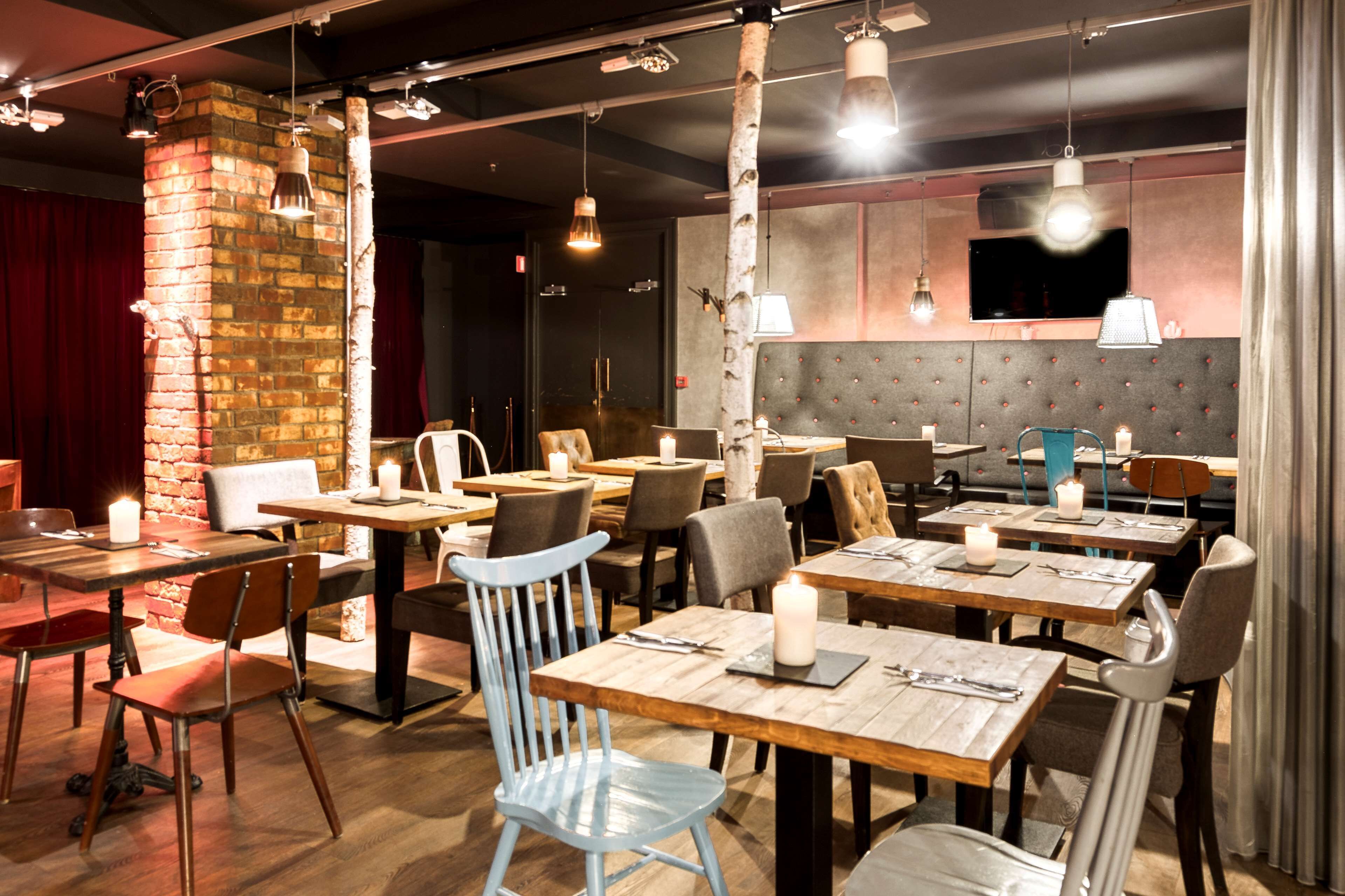 Un restaurant avec des tables, des chaises et des luminaires suspendus, le tout en bois.