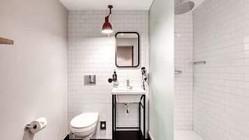 A modern bathroom with white subway tiles, a black sink, a toilet, and a shower area.