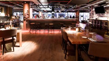 A modern restaurant with a bar area, wooden flooring, and bar stools.
