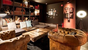 Un rincón acogedor para leer, con sofás de cuero, una mesa de centro de madera y una estantería llena de libros.