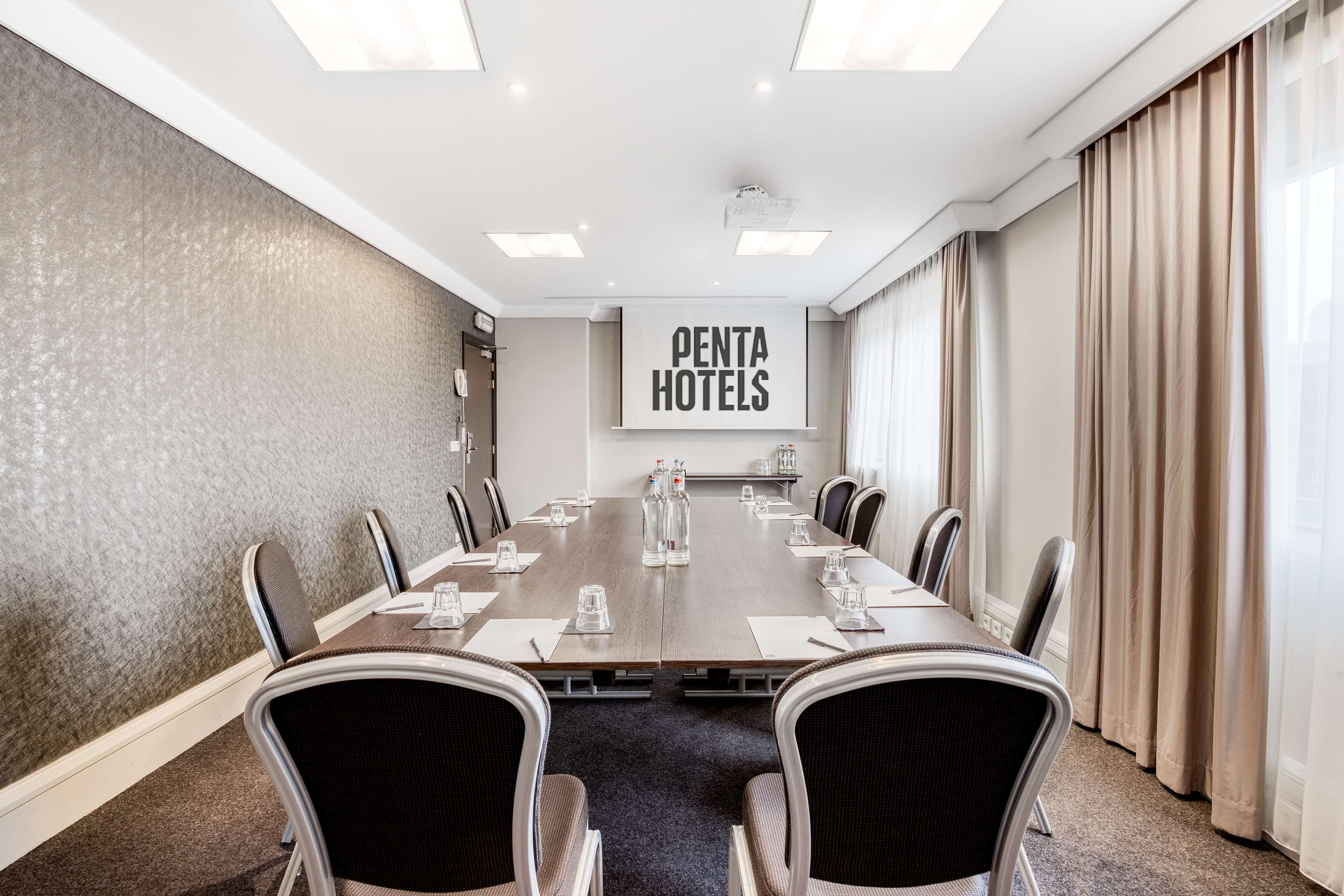 A conference room with a long table, chairs, and a sign for Penta Hotels.