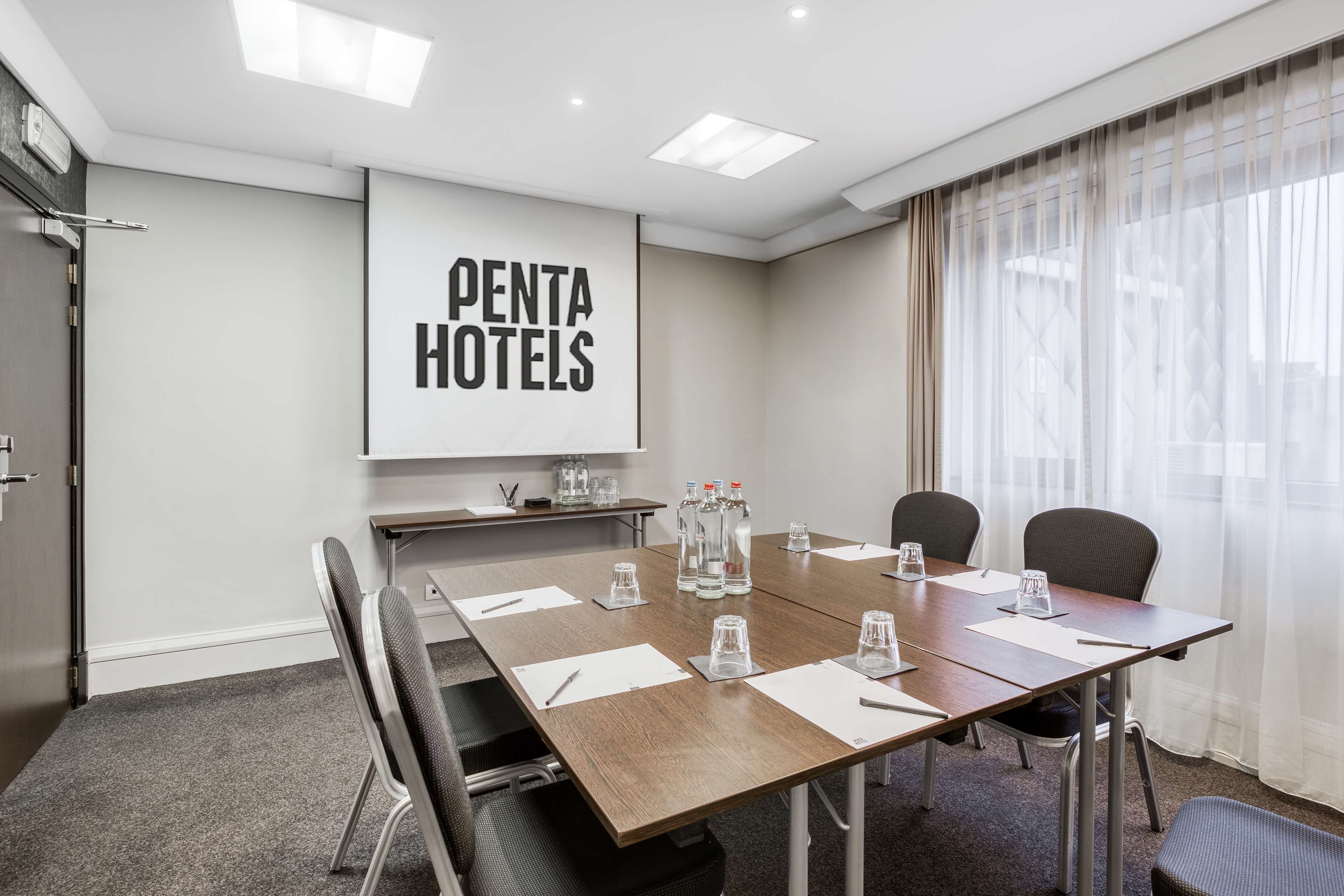 A conference room with a large table, four chairs, and a projector screen displaying "PENTA HOTELS".