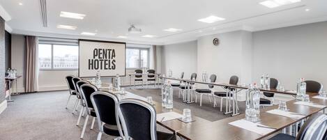 Un salón de conferencias con una pantalla grande que muestra
