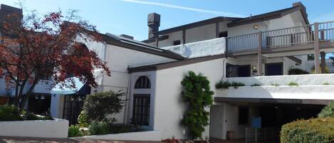 A multi-story building with a white facade, a covered entrance, and a visible balcony on the upper floor.