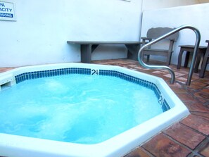 Una piscina con una escalera de metal, un banco y un cartel en la pared.