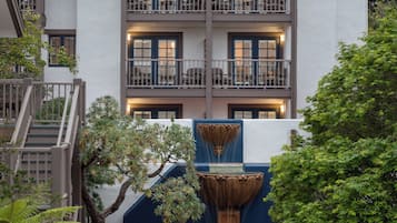 Un patio con mobiliario exterior, una fuente y un edificio con varios balcones.