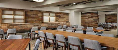 A conference room with a long wooden table, multiple chairs, and a herringbone-patterned floor.