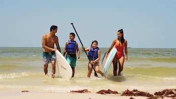 A group of people walking on a beach with surfboards.