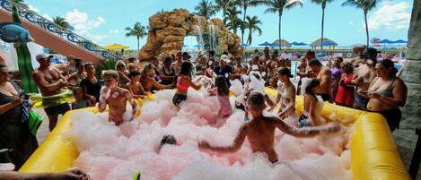 Eine Gruppe von Menschen rutscht auf einer großen, aufblasbaren Wasserrutsche in einem Resort.
