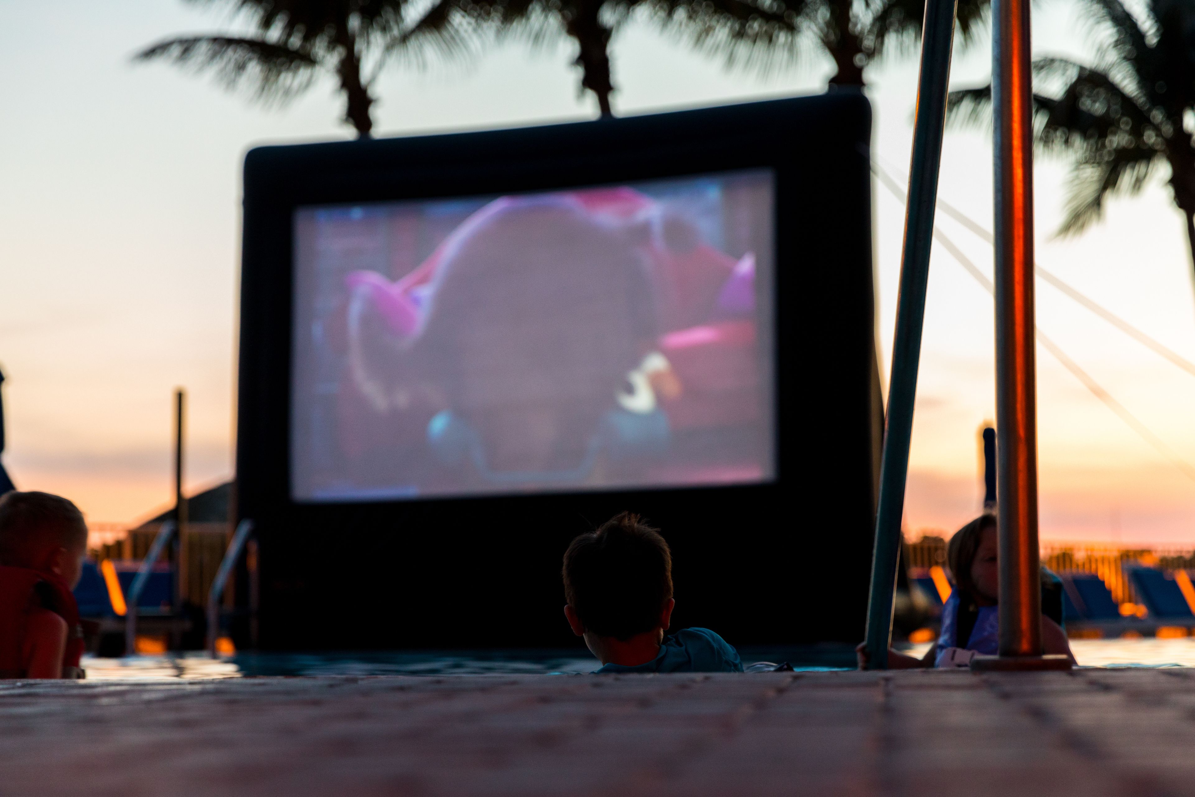 A child watching a movie on a portable TV screen outdoors at dusk.