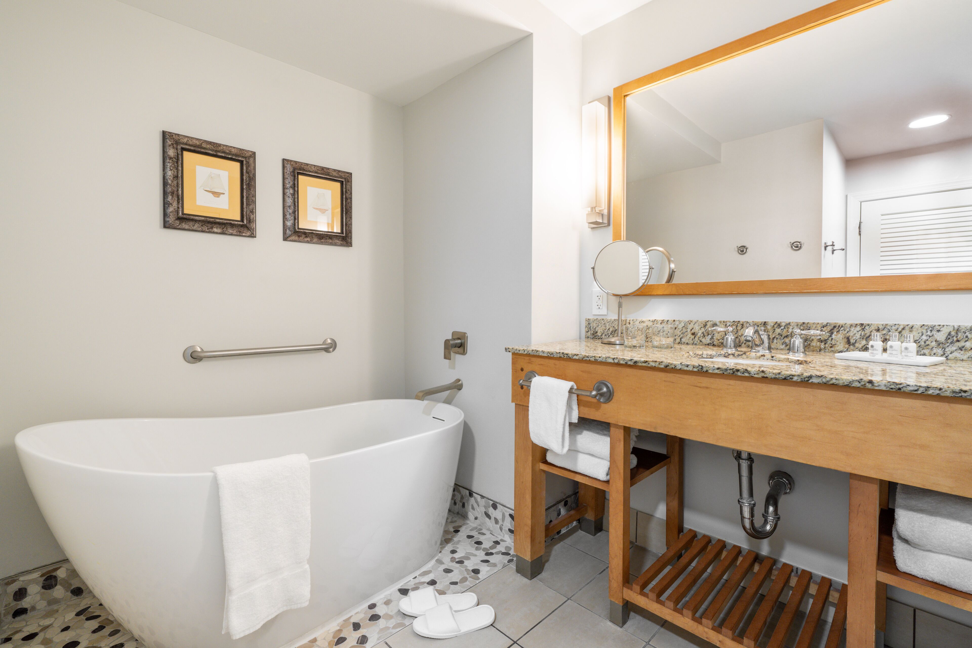 Un baño moderno con bañera independiente, tocador de madera y un espejo grande.