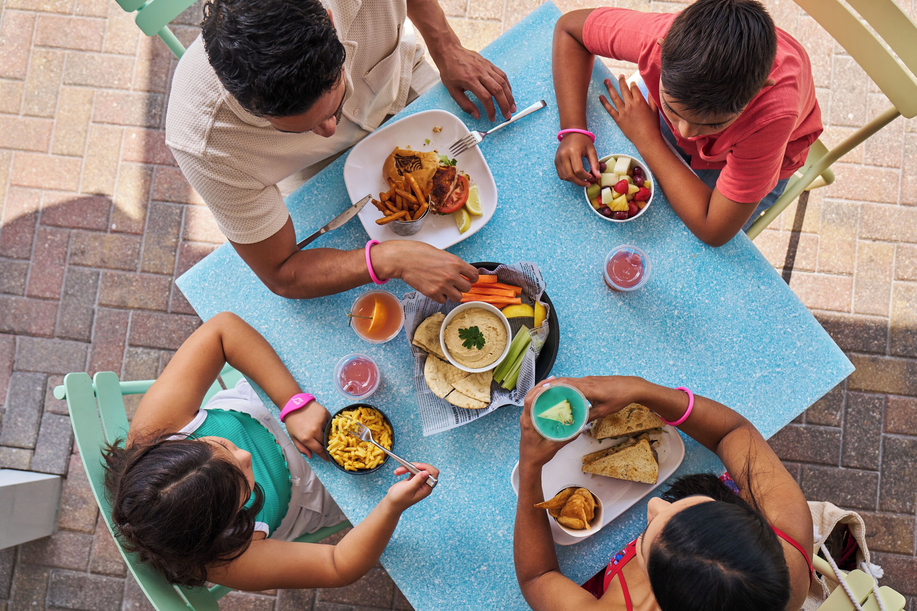 A group of people dining at an outdoor table with various dishes and drinks.