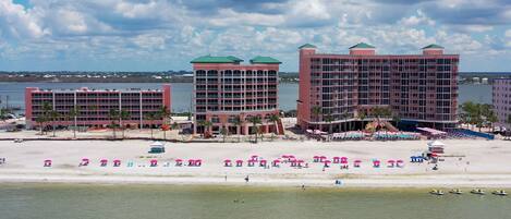 A beachfront hotel with multiple buildings, a sandy beach, and a water body in the background.