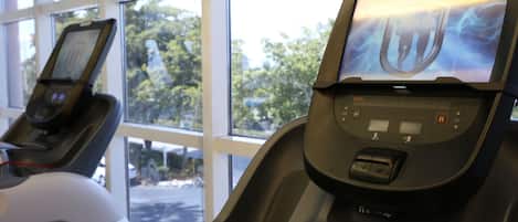 Un gimnasio con cintas de correr y un ventanal grande.