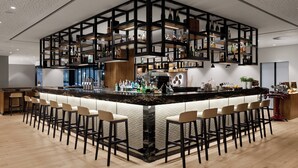 Een moderne bar met een centraal eiland, diverse zitmogelijkheden en een scala aan flessen en glazen op planken.