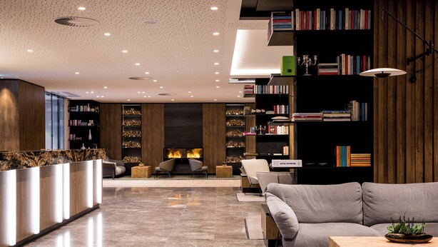 Een moderne lobby met een receptiebalie, een zithoek en een open haard.