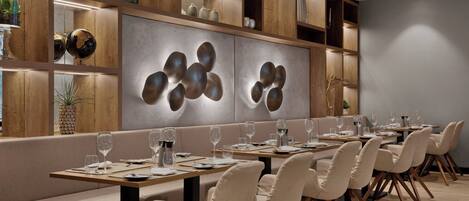 A modern dining area with wooden paneling, a long bench, and multiple tables with chairs.