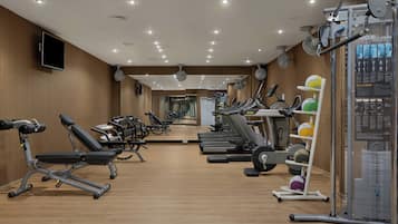 Un gimnasio con equipo de ejercicio, un televisor y un espejo grande.