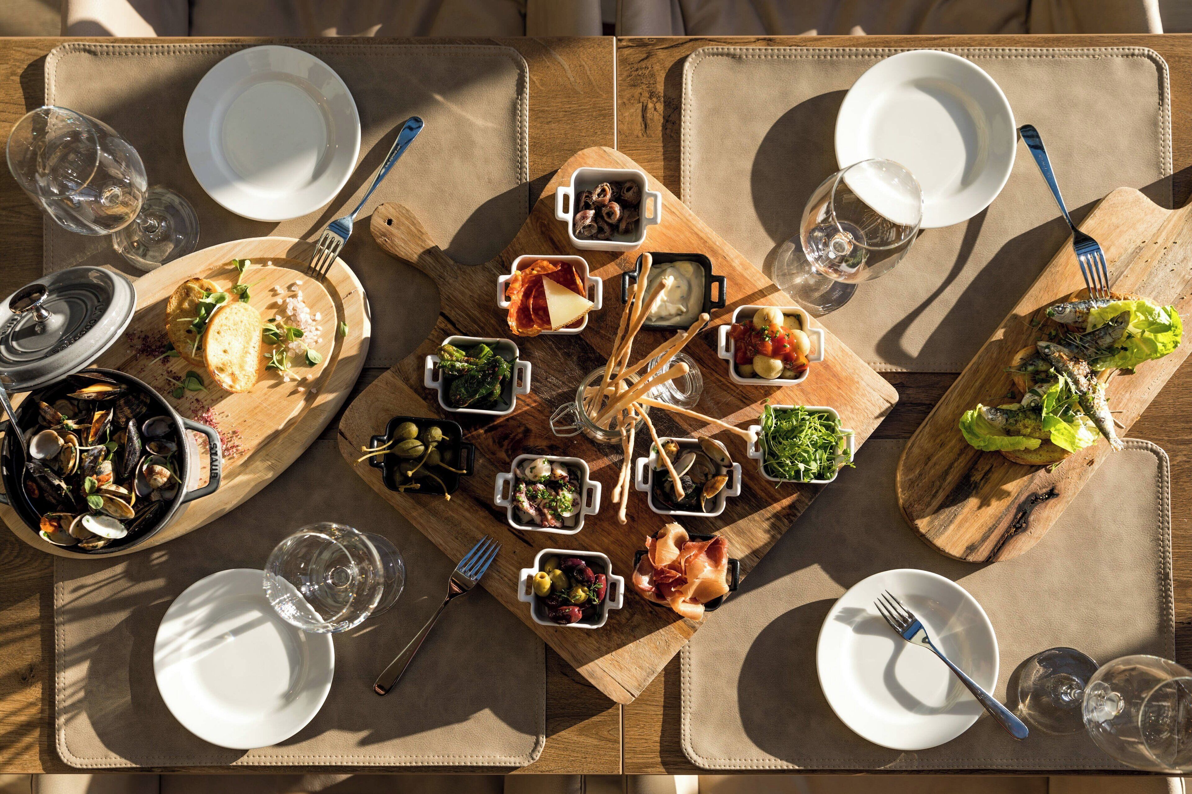 A dining table set with multiple dishes, glasses, and cutlery, suggesting a meal setup.