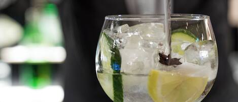 A glass of a clear beverage with ice cubes, garnished with a slice of lime and a star anise.