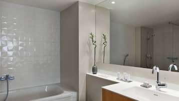 A modern bathroom with a bathtub, a vanity with a mirror, and a shower area.