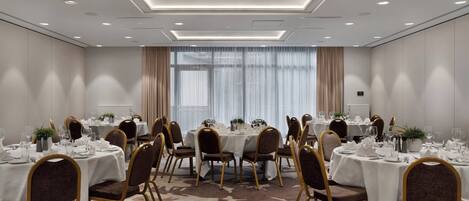 A conference room with round tables, chairs, and a carpeted floor.