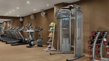 Ein Fitnessraum mit Laufbändern, einem Ergometer, einem Multifunktions-Trainingsgerät und einer Hantelbank.
