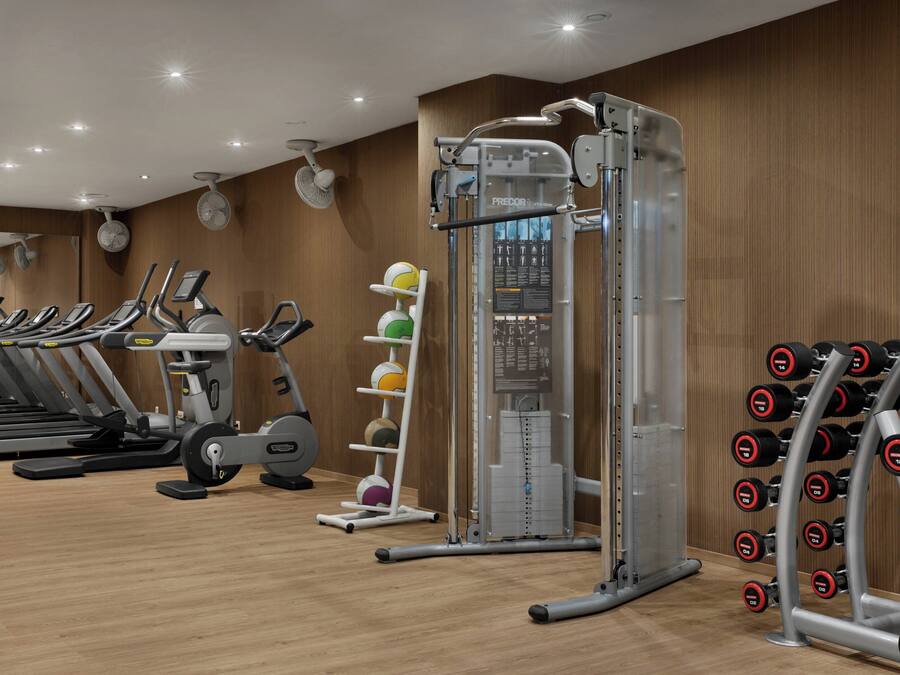 A gym with treadmills, a stationary bike, a multi-functional exercise machine, and a rack of dumbbells.