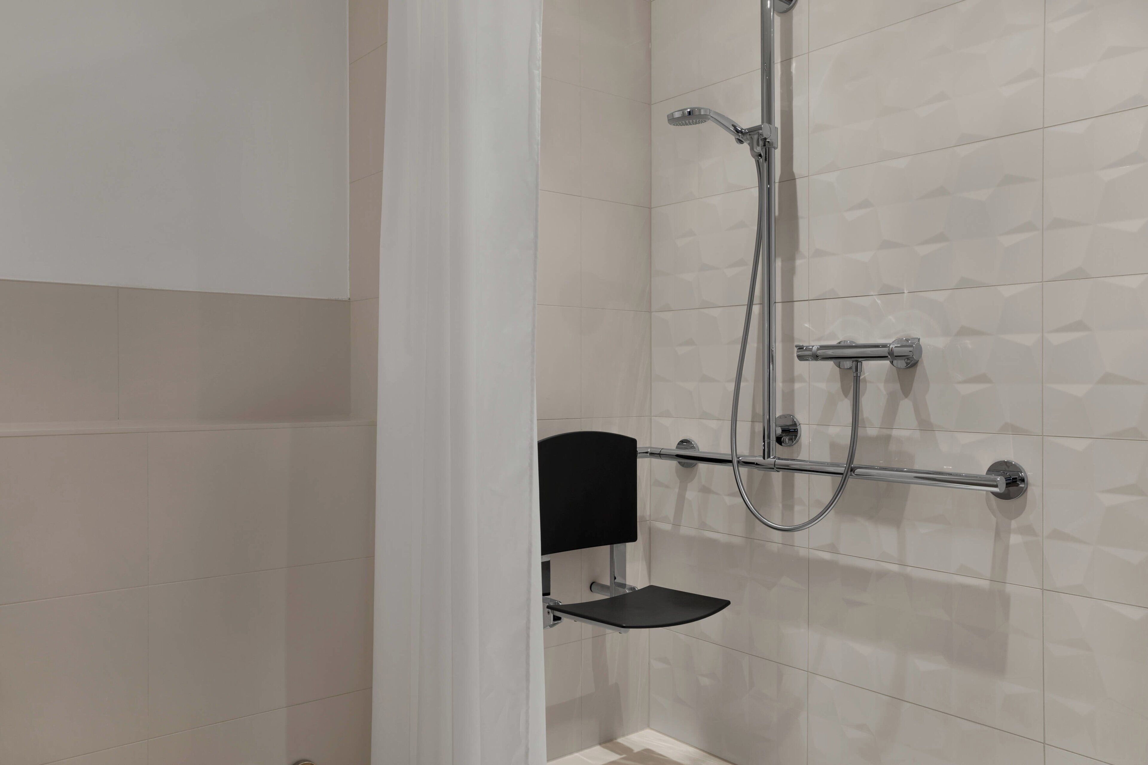 Ein modernes Badezimmer mit Dusche, einer schwarzen Seifenschale und einem Handtuchhalter.