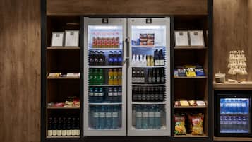 Dois dispensadores refrigerados de bebidas cheios de diversas opções, incluindo Pepsi, 7UP e água engarrafada, com interior em madeira e uma pequena vitrine à direita.