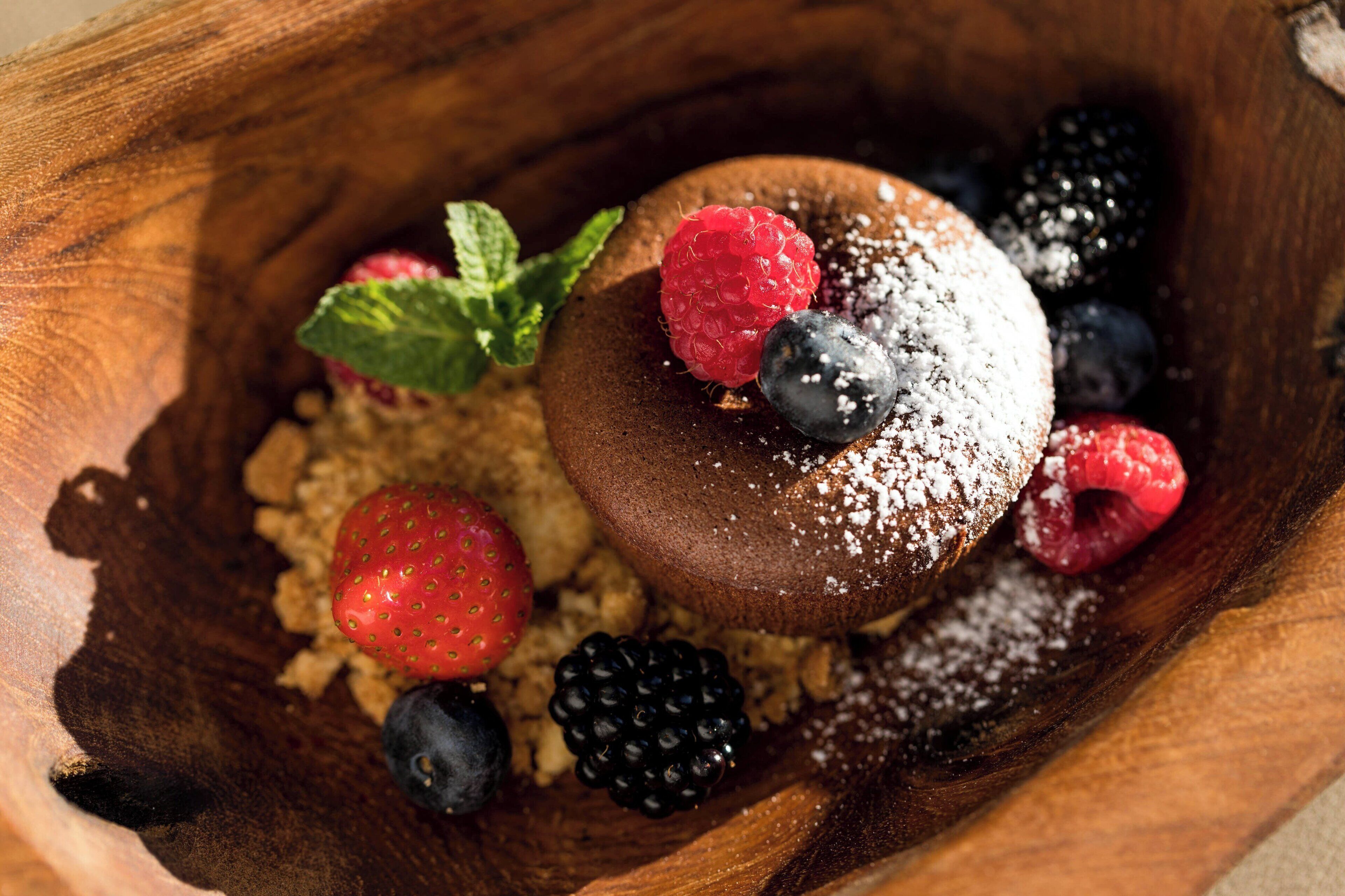 A dessert with berries and powdered sugar on a wooden surface.