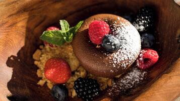 Un postre con frutos rojos y azúcar glas sobre una superficie de madera.
