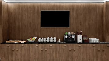 A modern kitchen with wooden cabinets, a flat-screen TV, and various kitchenware on the counter.