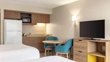 Habitación de hotel con cama, una mesita redonda, dos sillas, televisión, microondas y refrigerador.
