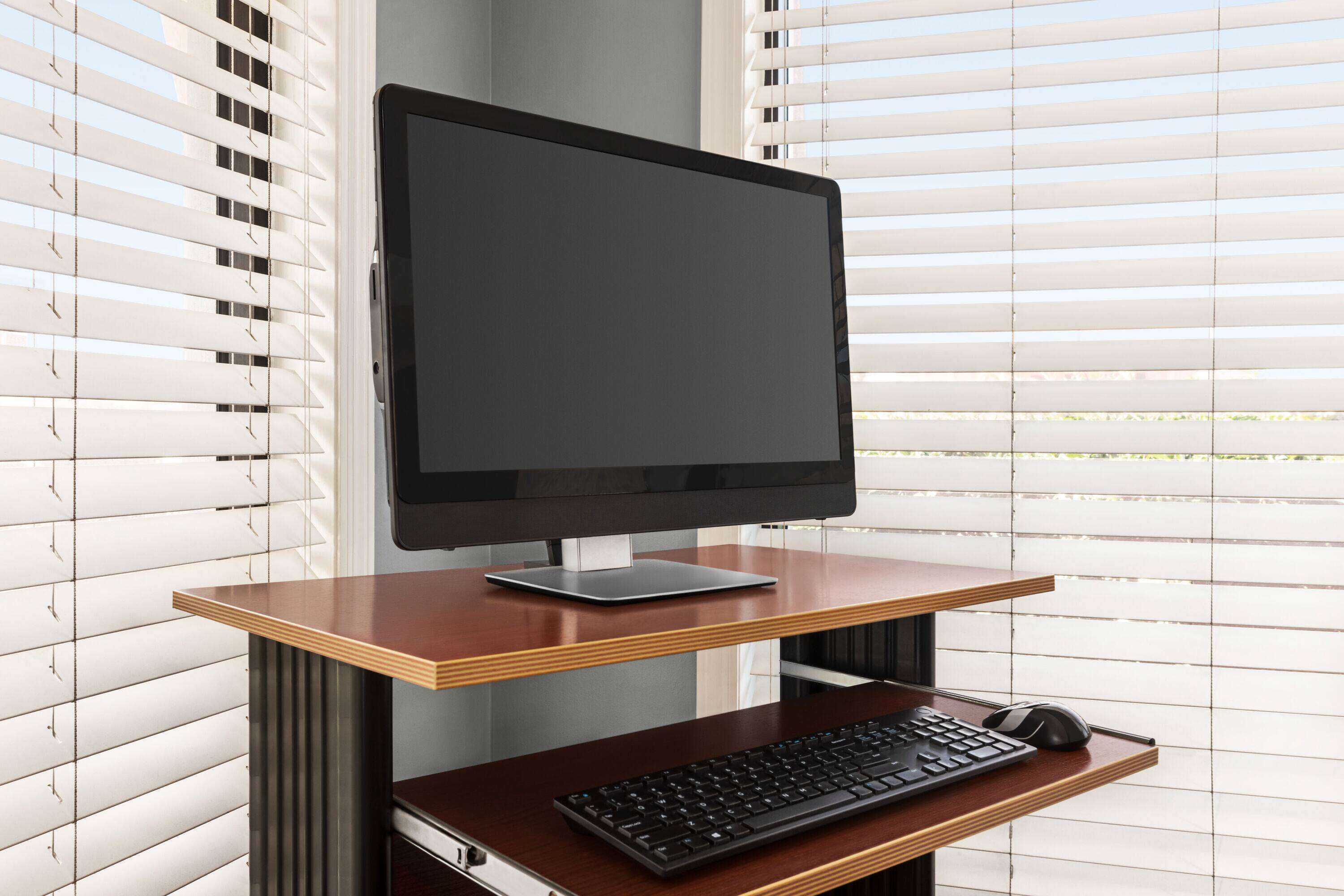A computer desk with a monitor, keyboard, and mouse.