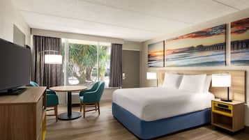 Relax in a spacious room with a large bed, flat-screen TV, and a desk area.