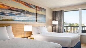 A hotel room with two beds, a large window with a view, and a painting of a pier on the wall. - Days Inn by Wyndham Cocoa Beach Port Canaveral (Cocoa Beach)
