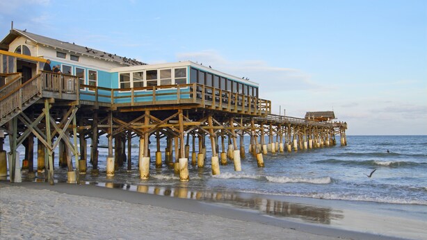 A wooden pier extending into the water with a building on it. - Days Inn by Wyndham Cocoa Beach Port Canaveral (Cocoa Beach)