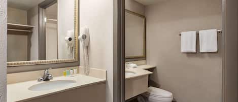 A bathroom with a sink, mirror, hairdryer, and toilet.