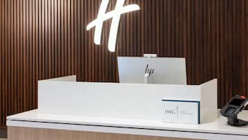 A reception desk with a white counter, a wooden backdrop, and a sign that reads "IHG ONE REWARDS".