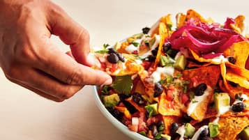 Een schaal met nachos en diverse toppings.