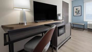 A modern kitchen with a flat-screen TV, a microwave, and a bench.
