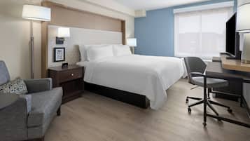 A hotel room with a bed, bedside tables, a desk with a chair, a TV, and a window.