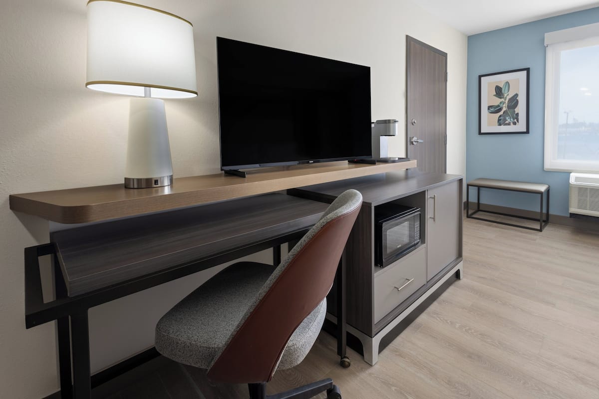 A modern kitchen with a flat-screen TV, a microwave, and a bench.