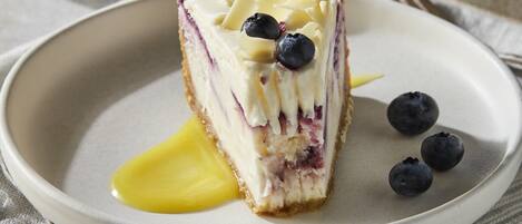 A slice of cake with blueberries and a dollop of cream on a plate.