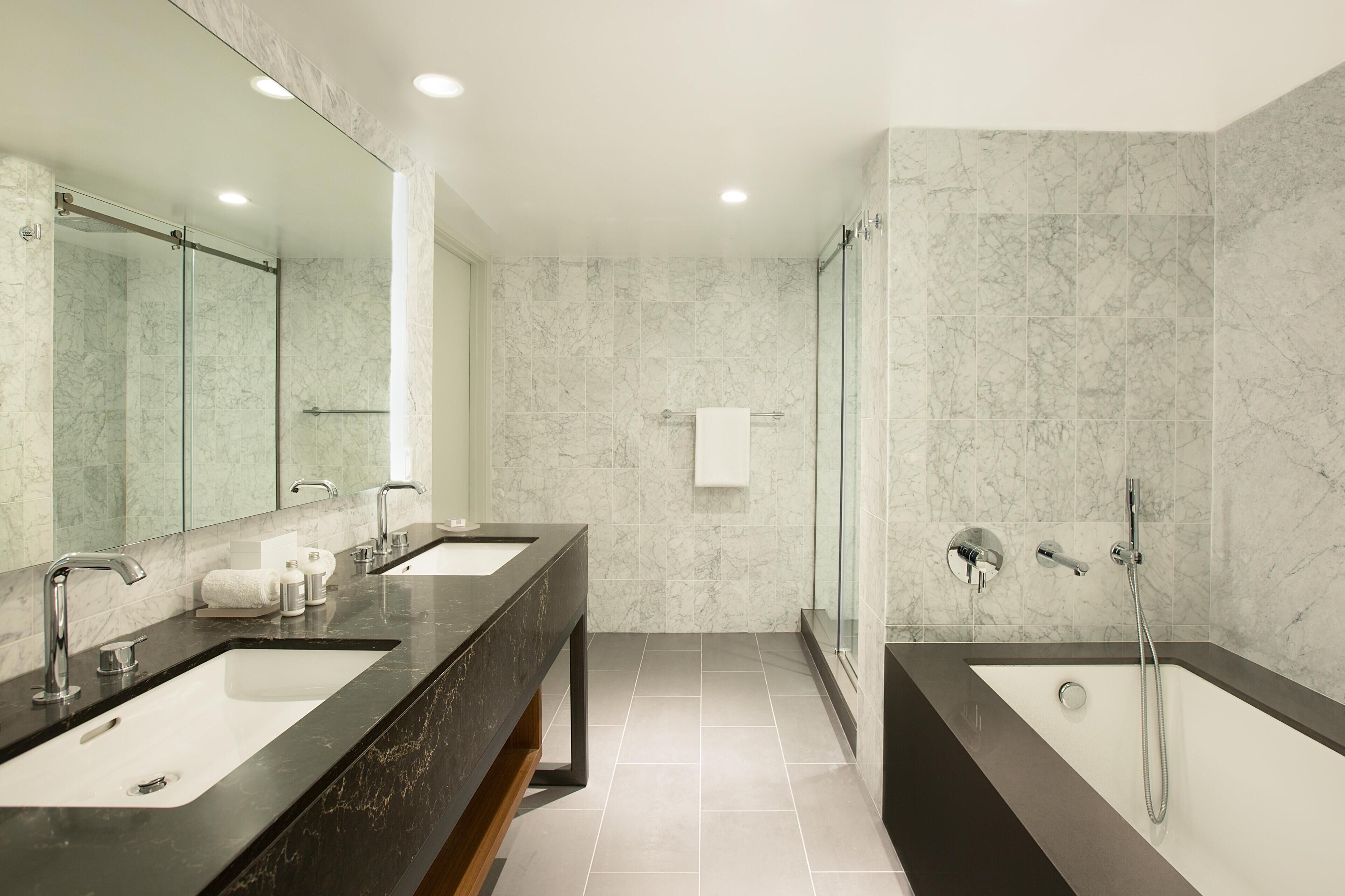 Un baño moderno con dos lavamanos, ducha y cabina de ducha con paredes de vidrio.