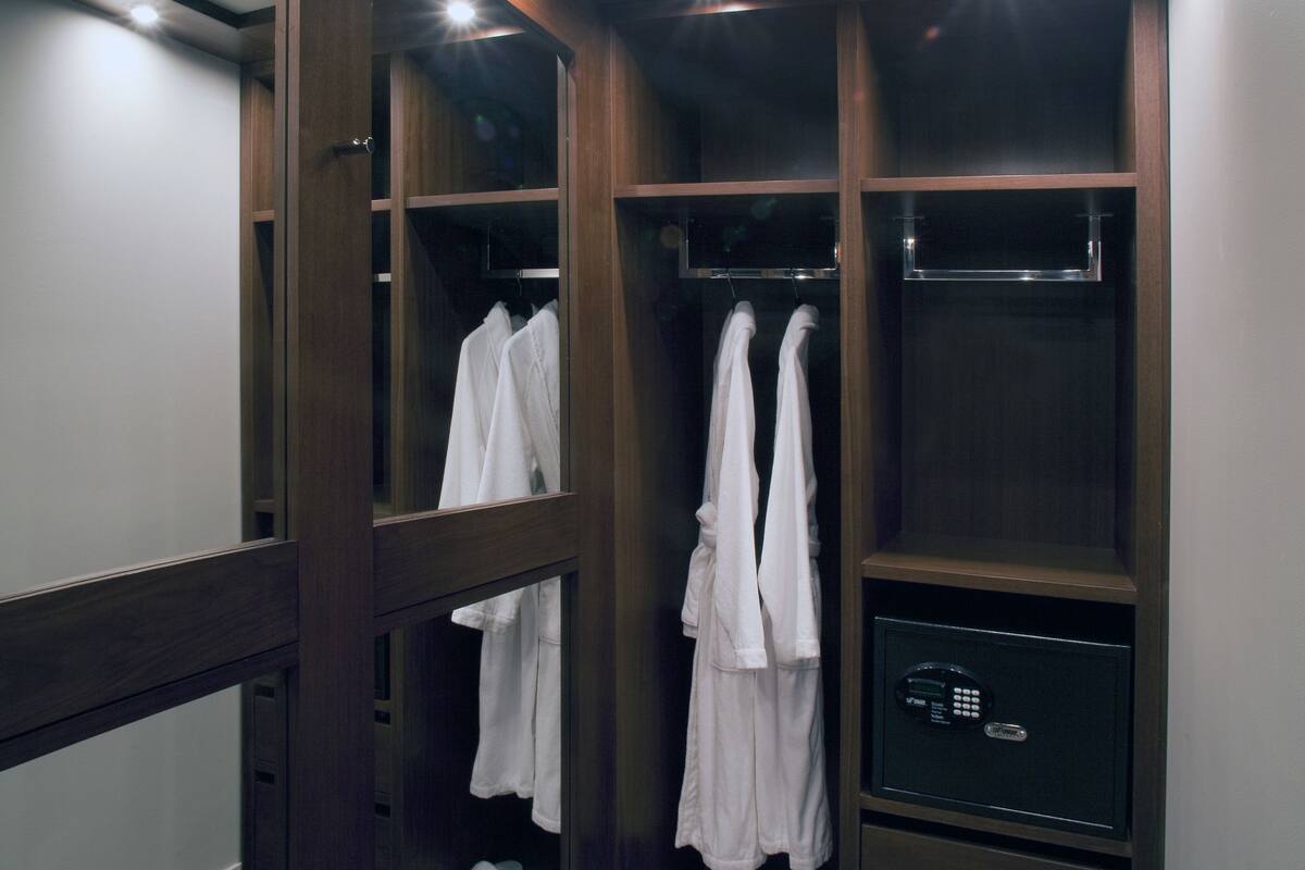 Vestidor con estantes de madera, zapatero y un espejo.