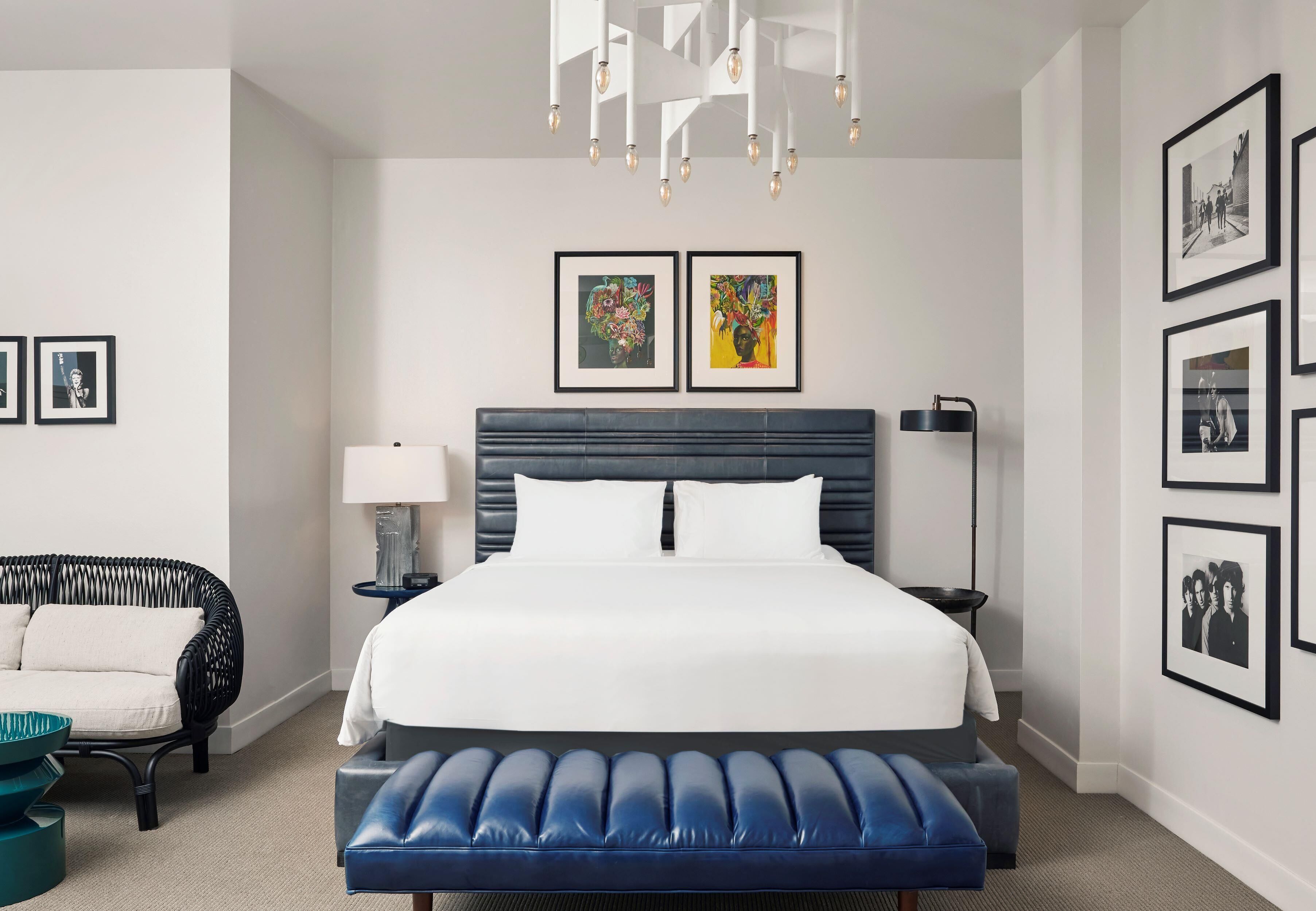 Una habitación de hotel moderna con una cama grande, un banco, un sofá y una araña.