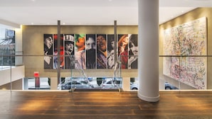 A modern interior with a staircase, a large abstract painting, and a view of the street outside.